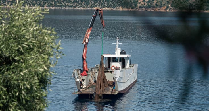A fishing boat pulling out plastic waste with a crane. Some of the plastic waste is made into sustainable floor mats for the IONIQ 5. 