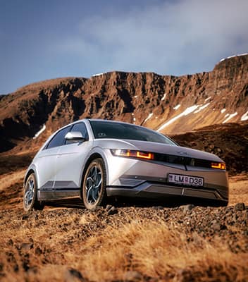 A gray IONIQ 5 standing alone with mountains in front of it.