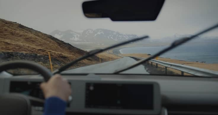 A view through the windscreen of the IONIQ 5 with mountains and lakes ahead.