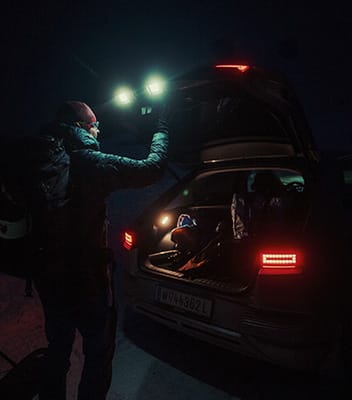 Photographer Nicholas Roemmelt opening the trunk of the IONIQ 5 in the dark guided by the car’s parametric lighting on the taillights and back door.