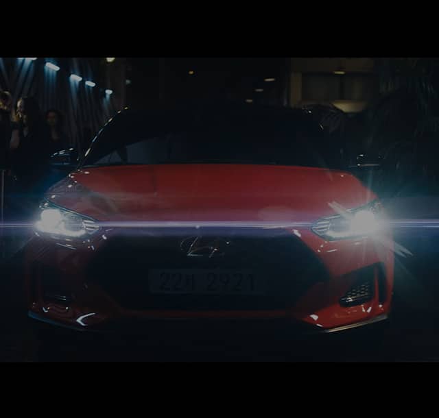 Front view of the red Veloster turn on its headlights.