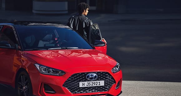 Right side front view of red veloster parking on the road